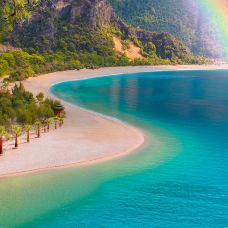A tranquil coastline in Turkey with a rainbow dipping in to the sea