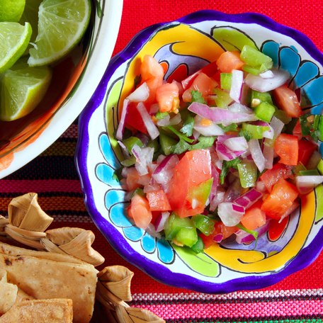 A fresh bowl of salsa with sliced limes