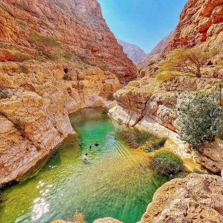 Hidden lagoon named Wadi Tiwi surrounded by red mountains in Oman 