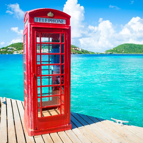 A red British phone box on a pontoon with British Virgin Islands in the background