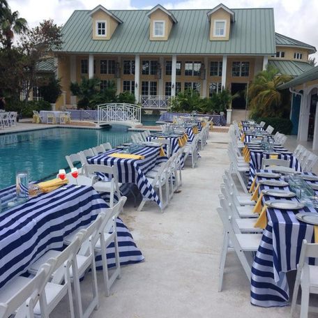 Tables laid with stripy table cloths by the poolside 