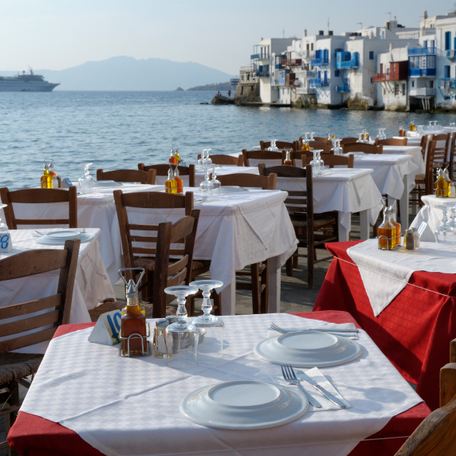 Two lines of dining tables at the water's edge in Mykonos