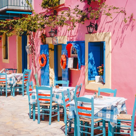 A cafe in the Mediterranean with pink walls and blue dining tables