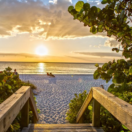 Wooden steps leading down to a beach at sunrise