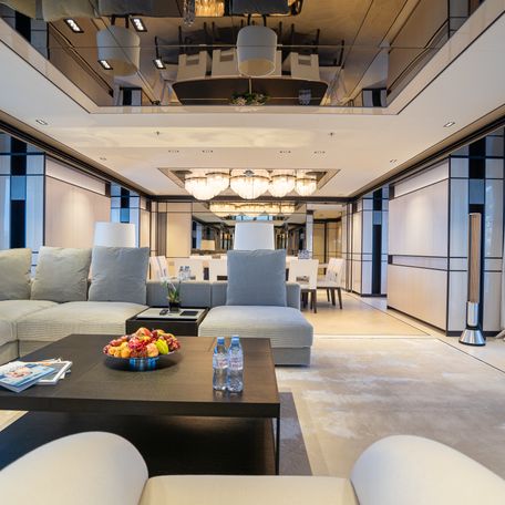 Overview of the main salon onboard charter yacht RELIANCE, seating area in foreground with dining area visible in background