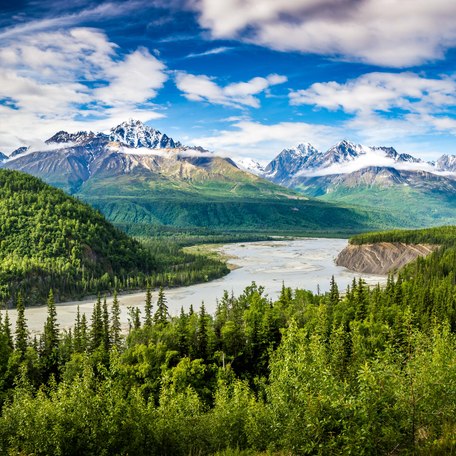 A winding river with snow-peaked mountains in the background