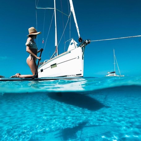 Shot of a woman paddle boarding in front of a yacht from below the waterline 