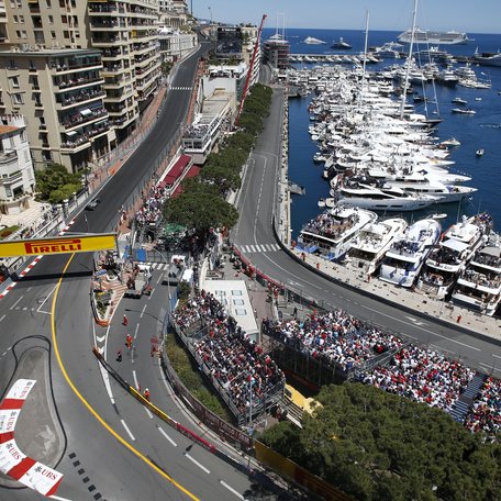 Elevated view looking down on Circuit de Monaco during the Monaco Grand Prix, with charter yachts berthed in the background
