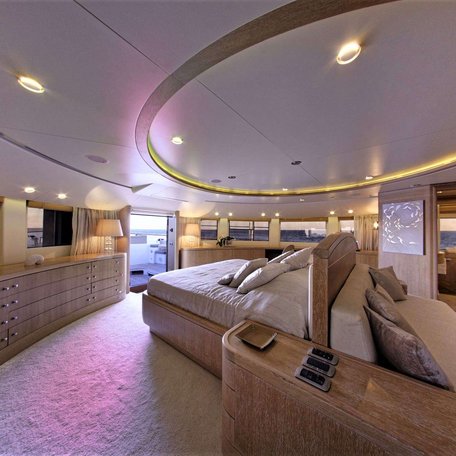 Overview of the master cabin onboard charter yacht GRANDE AMORE, central berth facing port with large windows and a desk in the foreground. 