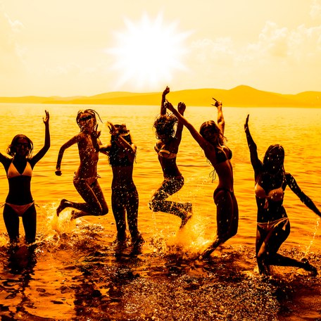 Charter guests jumping and dancing in the sea at sunset