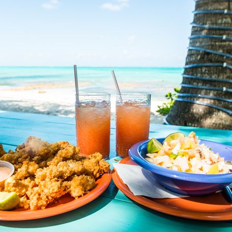 An authentic Caribbean meal and drinks on a table on a Caribbean beach