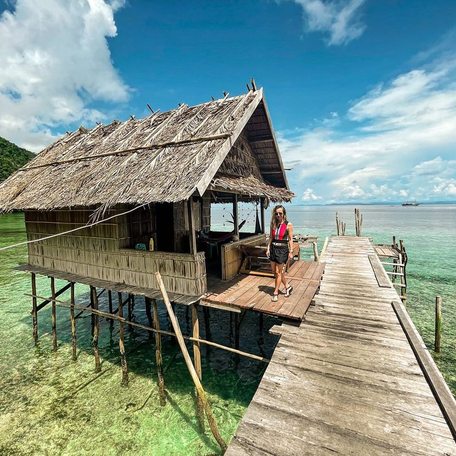 Woman standing on a jetty outside her homestay in a wooden house