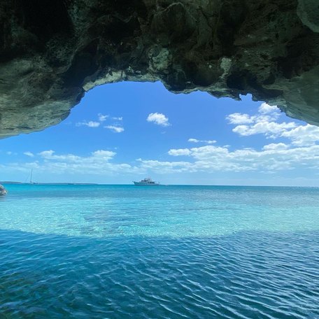 View from the mouth of a cave over Marsh Harbour waters while a boat cruises across