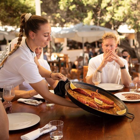 Server with a large platter of food at Cala Bassa