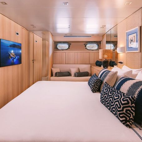 Overview of a cabin onboard charter yacht ISLANDER II. Central berth facing port, opposite a wall mounted TV. 