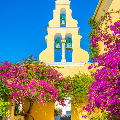 View of church bells through purple flora in Greece