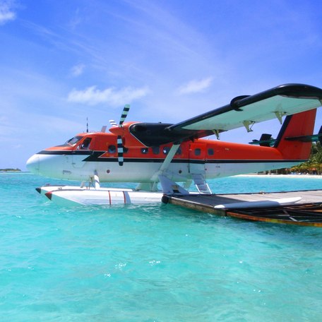 A red seaplane flying over the islands in the Maldives
