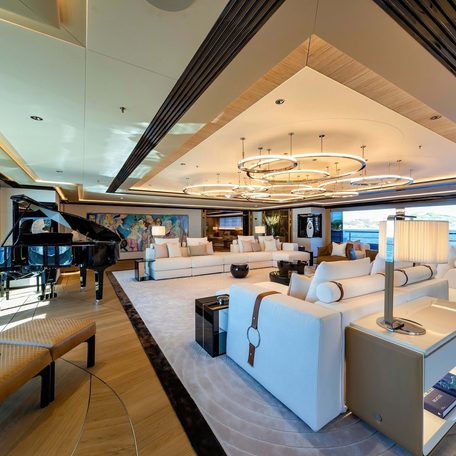 Overview of the main salon onboard charter yacht PROJECT X, large open lounge area with a grand piano visible