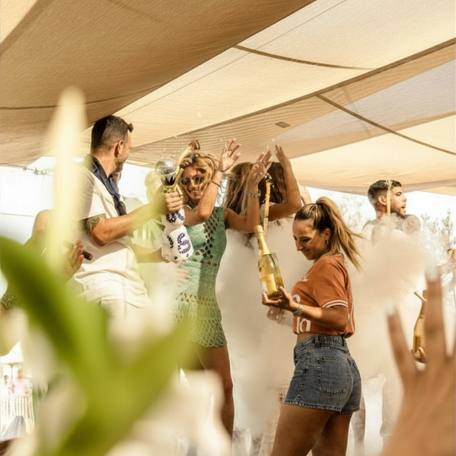 Charter guests dancing with champagne bottles at Les Palmiers St Tropez