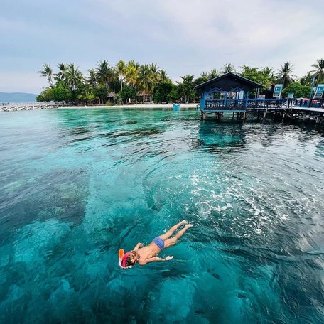 Girl floating in bright blue waters by the pier 