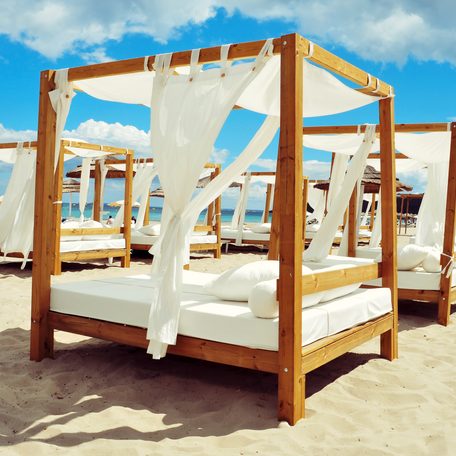 Lines of four-poster beds on a beach in Ibiza