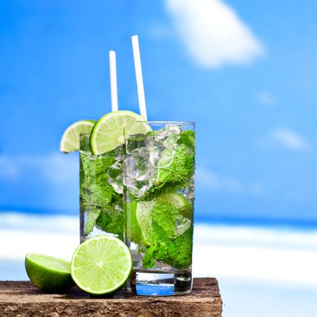 A pair of mojitos on a table by the beach