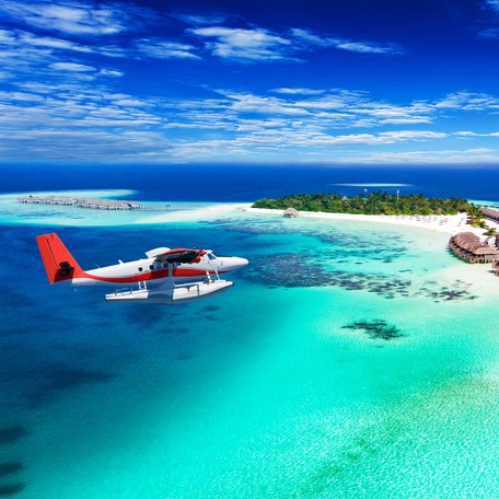 A seaplane in the air flying around the Maldives