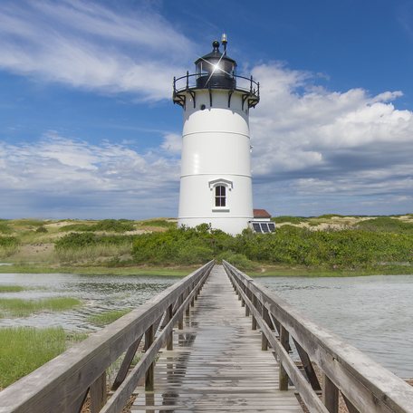 New England lighthouse with wooden boardwalk leading to it