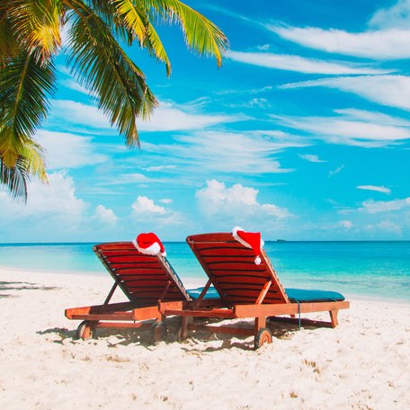 A pair of sun loungers on a Caribbean beach with Christmas hats