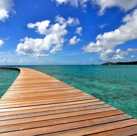 Wooden jetty and beautiful white cumulus clouds in the sky