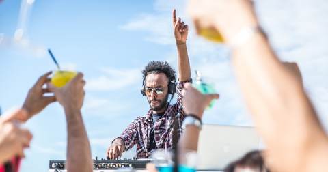 DJ raising his hand, dancing at a beach club in Ibiza