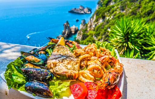 Greek cuisine on a ledge overlooking a cliff and azure waters below