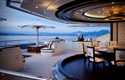 Exteriors onboard superyacht charter ALFA NERO with dining area in the foreground