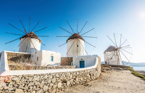 three white stone windmill on a hilltop in Santorini, Greece