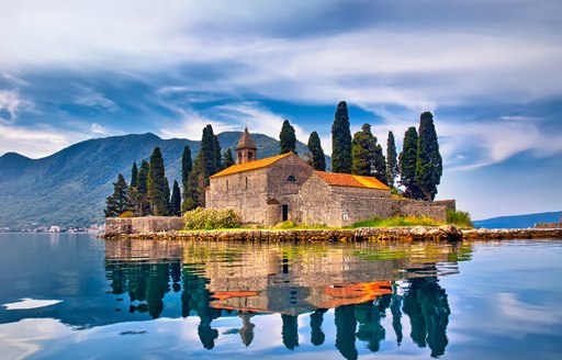 island in montenergo with buildings on it and pine trees in background