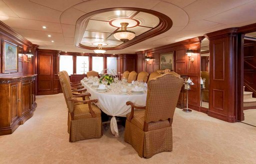 Interior formal dining area onboard charter yacht NOMAD, with a long table and white tablecloth set for a meal