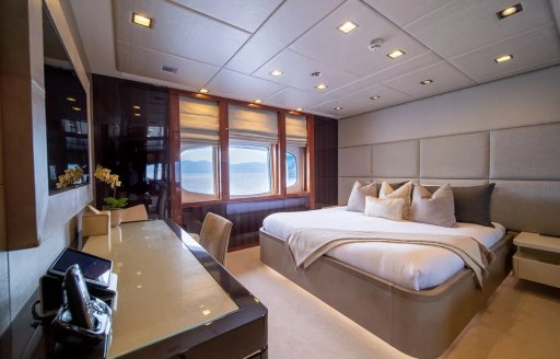 Overview of a guest cabin with central double berth and a large window onboard superyacht charter HOLDIN' MY OWN