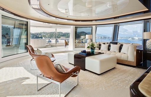 Well lit lounge area with cream seating and full-height windows onboard superyacht charter EXCELLENCE