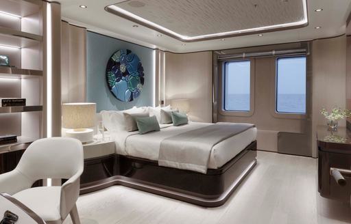 A guest cabin onboard charter yacht MALIA with a central berth, dressing table in the foreground and two windows in the background