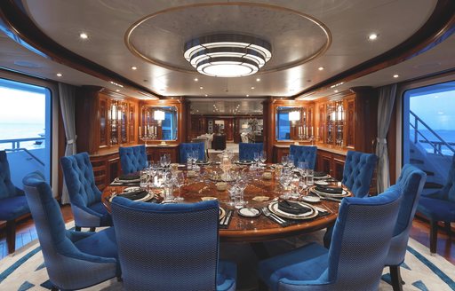 Circular dining table with blue upholstered seats onboard superyacht charter TITANIA