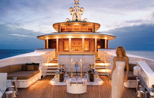 Charter guest on the sundeck of luxury yacht UTOPIA at night, illuminated by lighting panels