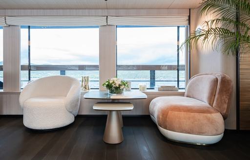 Interior seating area onboard charter yacht M with two armchairs and large window