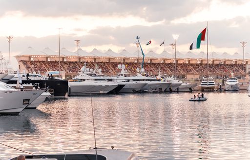 Superyachts in foreground at Yas Marina during F1 Abu Dhabi Grand Prix with grandstands in background