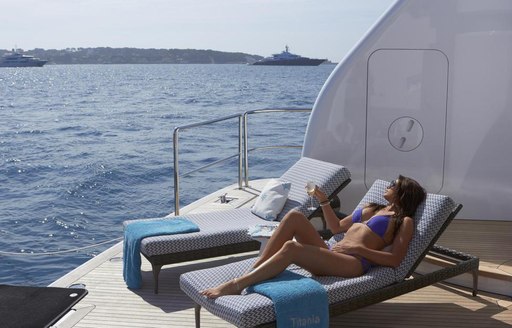 a charter guest enjoys the sundeck of her luxury yacht