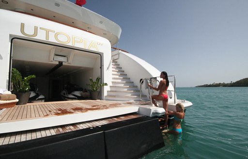 Swim platform and beach club on megayacht UTOPIA, with charter guests climbing on board from stairwell