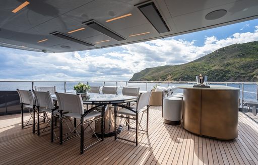 Alfresco dining area onboard charter yacht M with long table and directors chairs