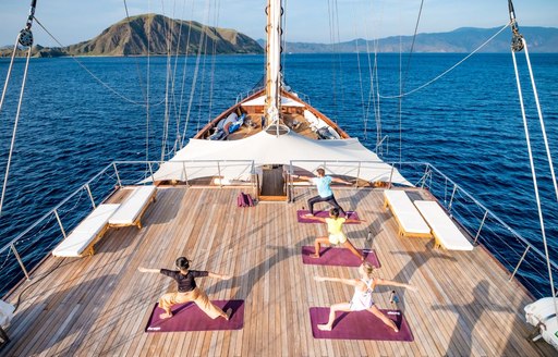 Guests of LAMIMA yacht doing yoga session on deck aerial shot