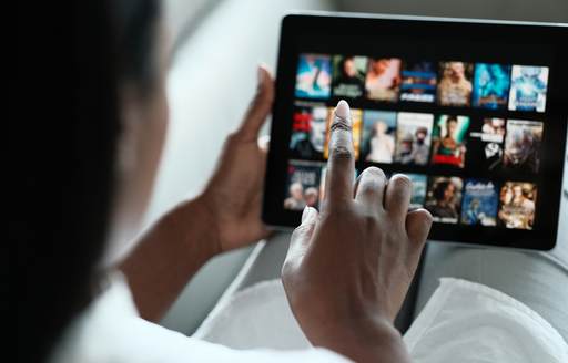 A woman selecting a movie from a portable touch screen tablet on board a yacht