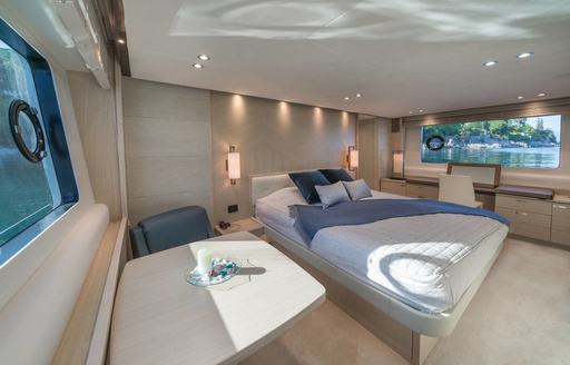 Master cabin with central berth and a desk in foreground onboard charter yacht LARIMAR II