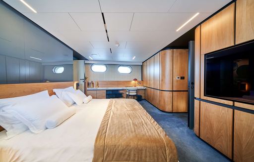 Master cabin with central berth and blue carpet onboard yacht rental MARALLURE